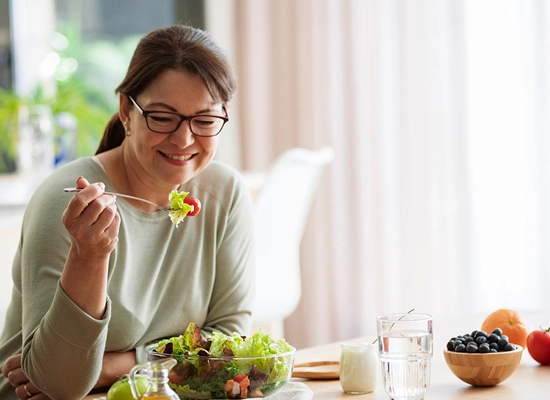 Woman eating salad at kitchen counter